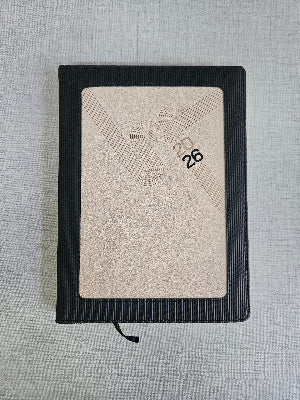 Black leather-bound notebook with embossed design on a textured gray background