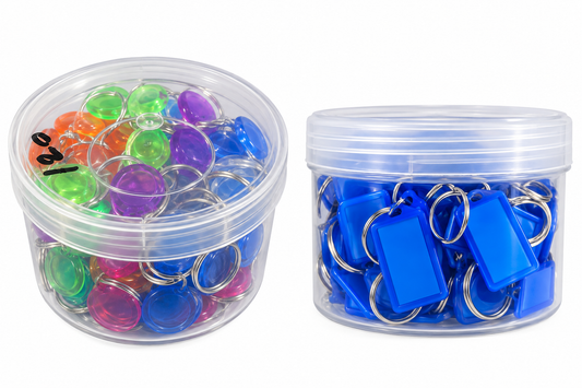 Two clear plastic storage containers on a white background. The left container holds assorted translucent round keychains in multiple colors including green, purple, orange, and blue.