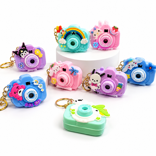 A set of colorful camera-shaped keychain charms and a matching camera-shaped case, shown on a clean white background. The charms come in multiple pastel colors including pink, blue, purple, teal, and mint green, each decorated with cute cartoon animal faces, flowers, stars, and small accessories.