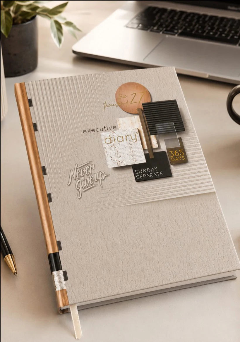 2027 cream and copper paper pasting executive diary V-364 with geometric collage cover, black and gold accents, Never Give Up lettering, and ribbon bookmark.